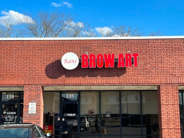 The Rani Brow Art storefront on Rock Springs Road, red brick with the studio sign above the glass door of suite 135